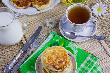 cup with tea, curd pancakes on a dish and milk