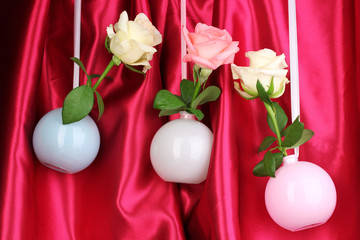 Beautiful roses in vases hanging on cloth background