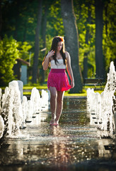 teen girl wearing red skirt playing at outdoor water fountain