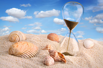 Hourglass in the sand with blue sky