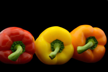 Red yellow and orange bell peppers isolated over black