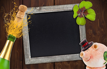 Kreidetafel mit Sektflasche, Schwein, Kleeblatt auf Holzwand