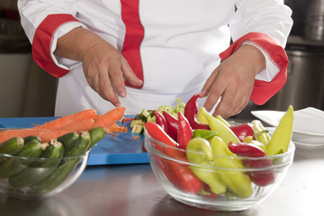 chef is preparing vegetable salad from a cabbage, tomato,