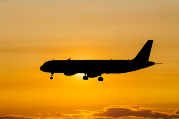 Silhouette of a passenger plane landing in sunset