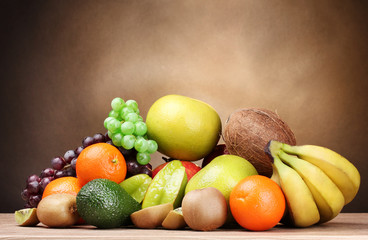Assortment of exotic fruits on wooden table on brown background
