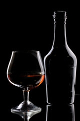 Glass of brandy and bottle on black background