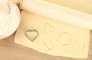tin of cookies on the rolled out dough on wooden table close-up