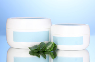Jars of cream with aloe vera on blue background