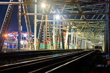 Fototapeta premium Old iron railway bridge for the passage of trains, at night.