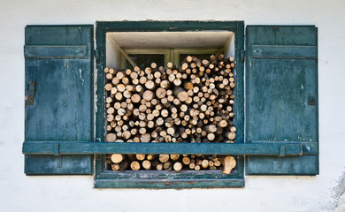 Weathered old window of an hermitage with firewood for the cold winter.