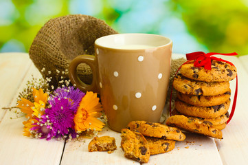 cup of milk, chocolate chips cookies with red ribbon and