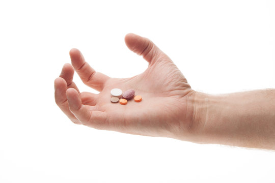 Hand holding pills in an angry or frustrated manner