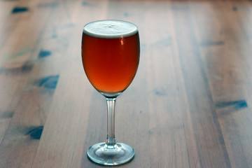 Belgian beer. Beer glass on wooden table in belgian restaurant.