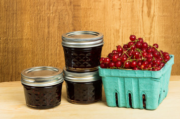 Red currant jelly and currants on wooden table