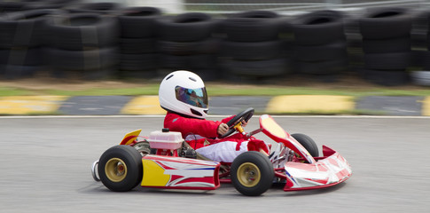 Young asian boy racing in a go kart - obrazy, fototapety, plakaty