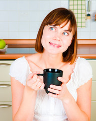 young  woman, enjoying a cup of coffee in her home.