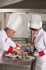 Two cooks working in professional industrial kitchen 