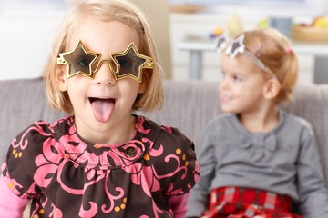 Obraz premium Little girl sticking tongue in star shaped glasses