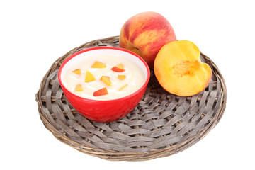 Yoghurt with peach in bowl on wicker mat isolated on white