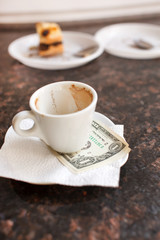 dollar bills under a coffee cup