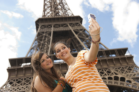 2 jeunes filles se prenant en photo devant la Tour Eiffel