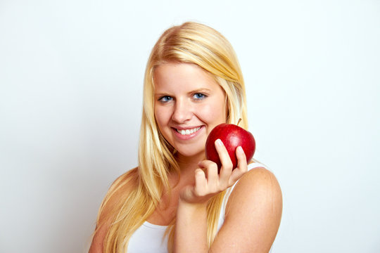 beautiful young blond smiling girl eating red apple