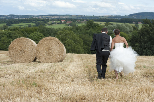 jeunes mariés courant dans un champs