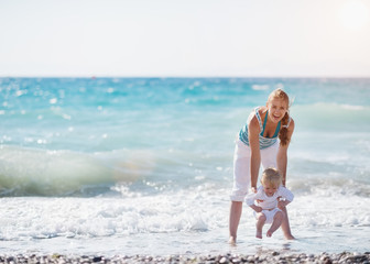 Mother and baby playing with sea waves