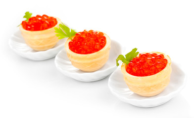 Red caviar in tartlets on little white saucers isolated on