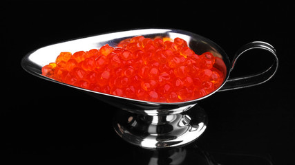 Red caviar in silver bowl isolated on black