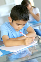 Closeup of young boy writing on notebook at school
