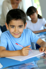 Portrait of smilng young boy sitting in classroom