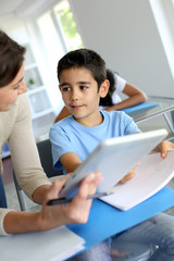 Teacher and schoolboy using electronic tablet in class