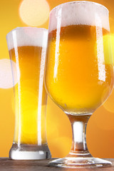 Beer into glass on golden background