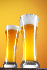 Beer into glass on golden background