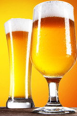 Beer into glass on golden background