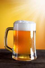 Beer into glass on golden background