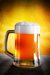 Beer into glass on golden background