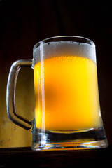 Beer into glass on golden background