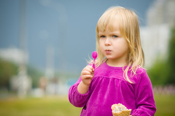 Adorable girl eat ice cream near mall on grass