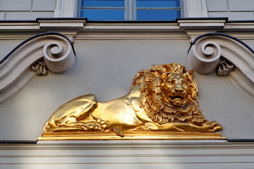 Lion doré sur façade ancienne.