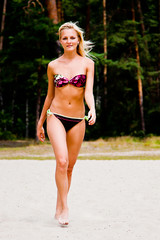 A young and beautiful woman walking along the sandy beach