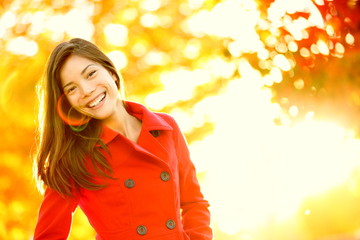 Autumn red trench coat woman in sunny tree leaves