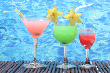 Glasses of cocktails on table on blue sea background