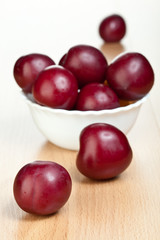 Ripe plums in a white bowl
