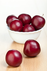 Ripe plums in a white bowl on a table