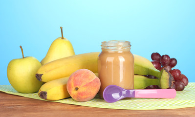 Jar with fruit baby food, spoon and fruits