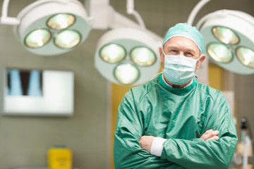 Fototapeta na wymiar Smiling surgeon crossing his arms while standing