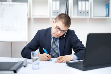 Portrait ofyoung business man writing on paperwork in office