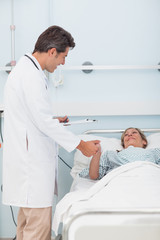 Obraz premium Doctor talking to his patient while holding her hand